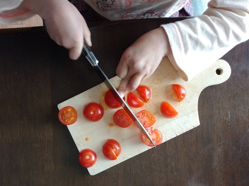 子供がペティナイフでトマトを切る